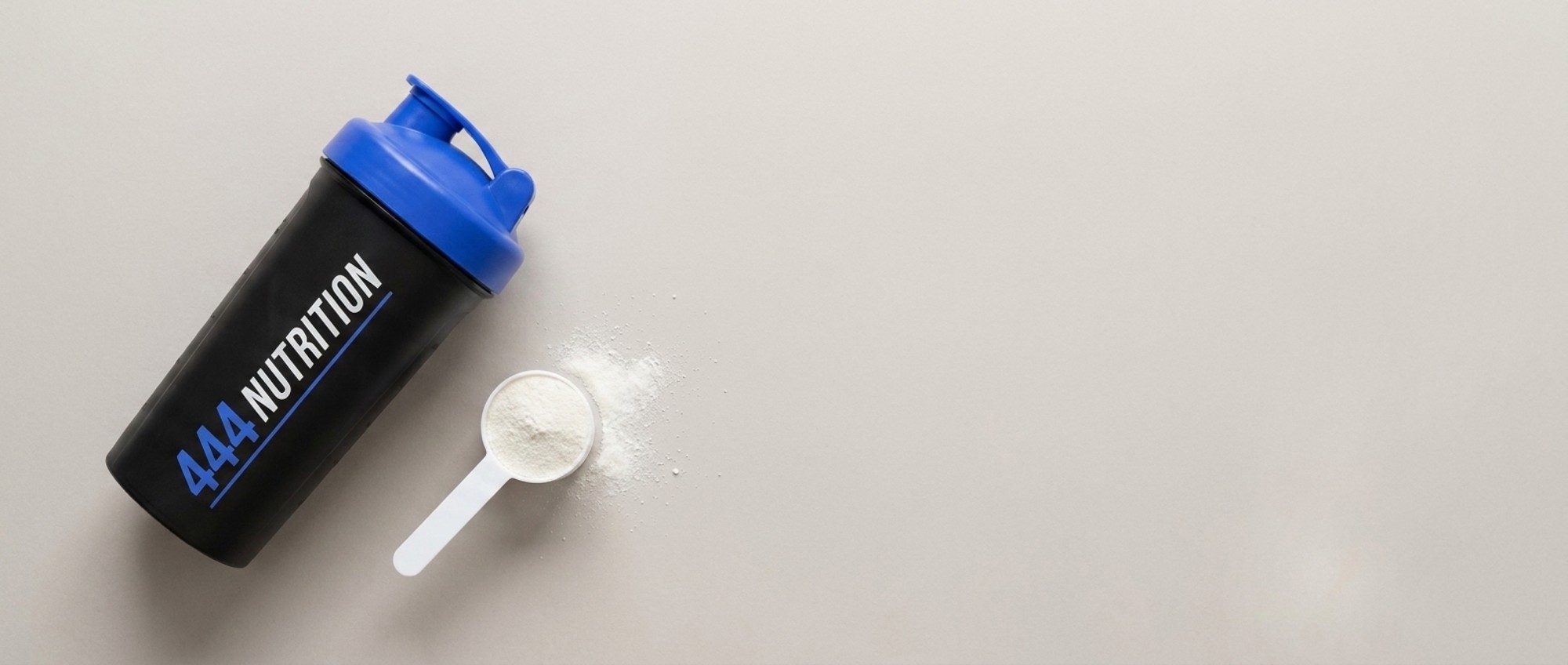 444 Nutrition shakebeker met blauwe dop en een maatschepje poeder, van bovenaf gezien
